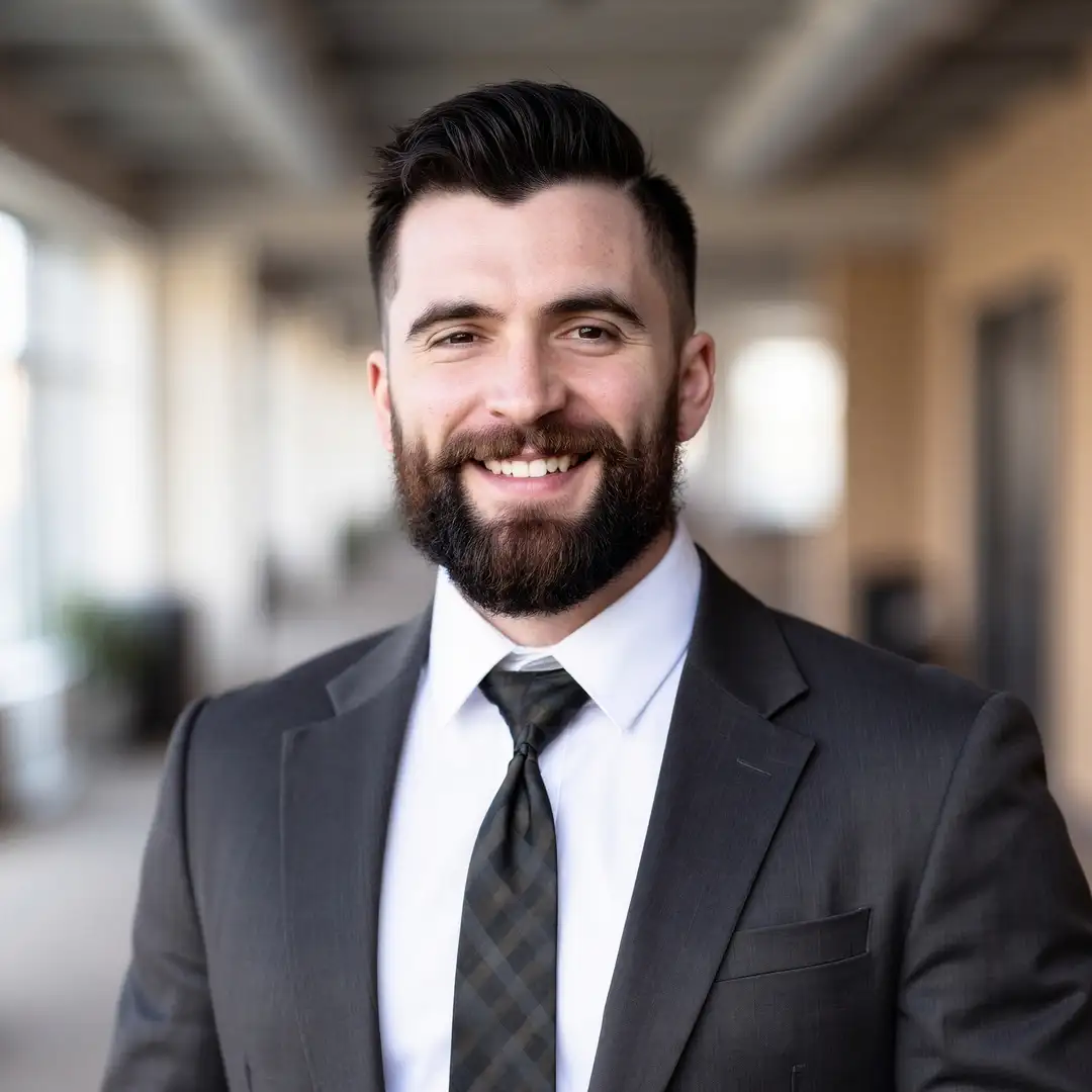 Smiling financial professional in a suit, representing Legacy Financial Group, with a modern office background emphasizing trust and expertise in financial planning.